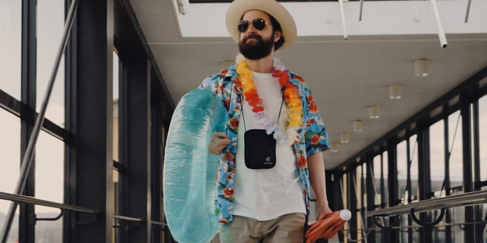 Man with summer hat, swim ring and summer clothes walks through ferry terminal.