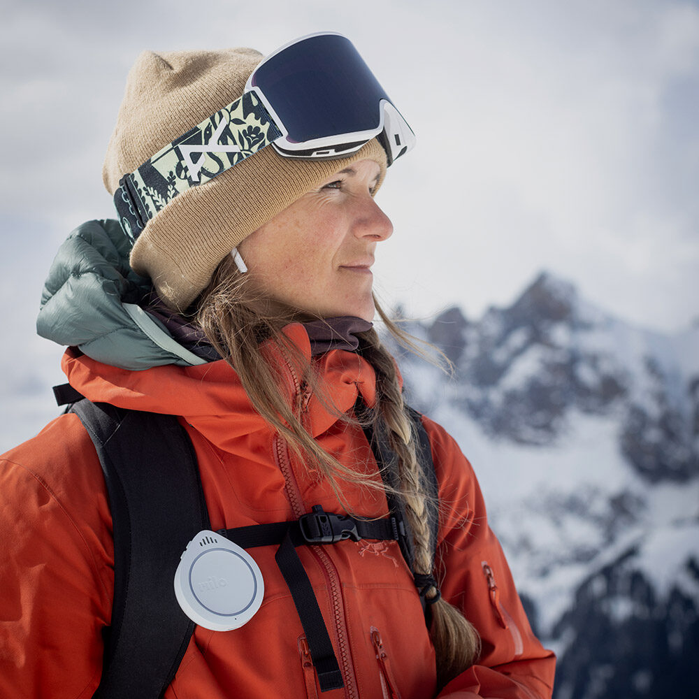 Close-up of woman wearing ski clothes. On her backpack is a Milo product.