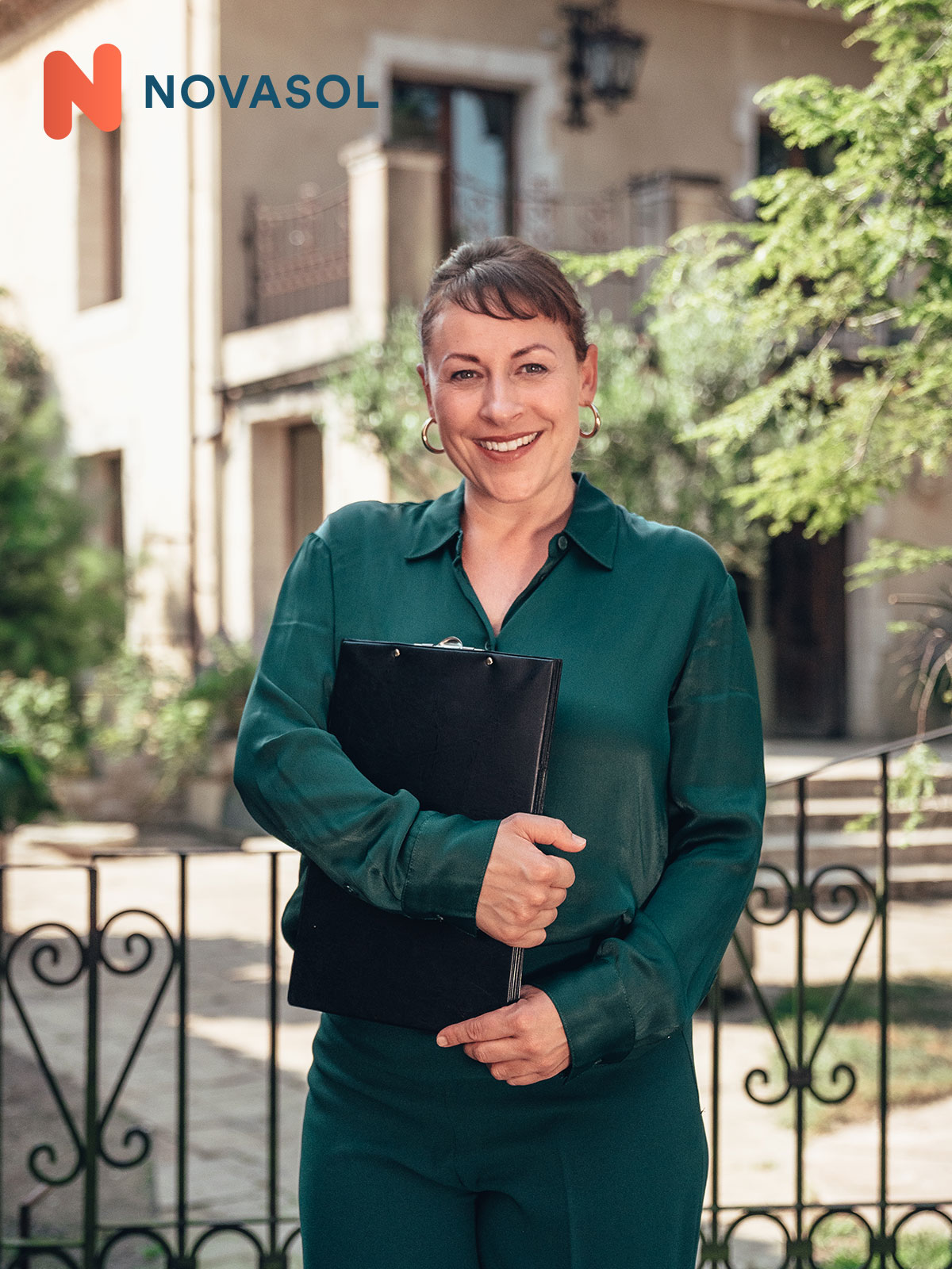 A female consultant from Novasol stands in front of a house.